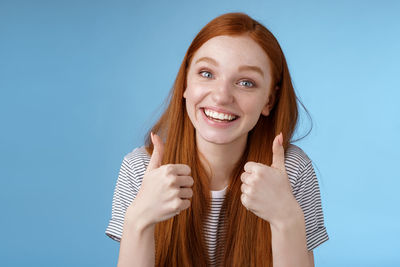 Happy woman with thumbs up against blue background