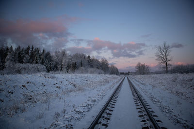 A beautiful winter morning landscape of a railway tracks in the forest. colorful sunrise scenery.