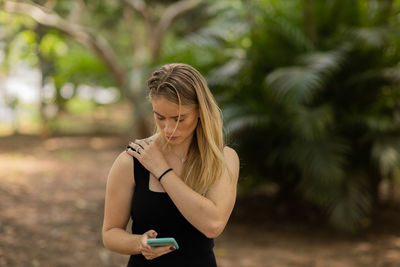 Woman using a smartphone at day time at a green park. mobile phone, technology, urban concept. 