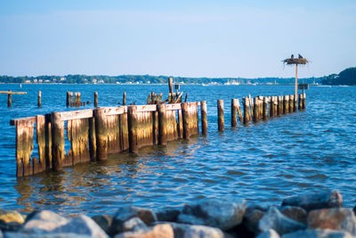 Wooden posts in sea against sky
