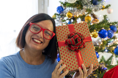 Portrait of young woman holding christmas tree