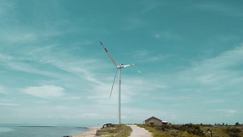 Traditional windmill by sea against sky