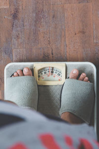 Low section of person standing on weight scale at home