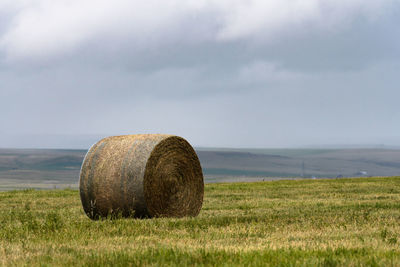 Hay bales on field against sky