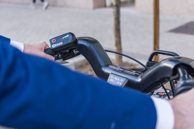 From above of crop anonymous male looking at lcd display with colorful symbols on electric bicycle