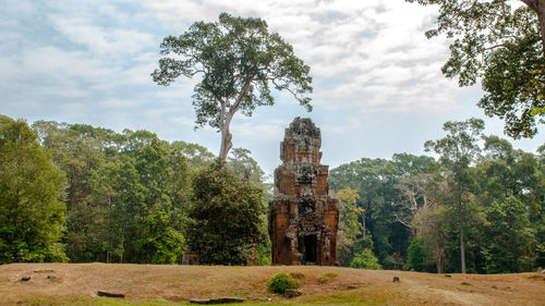 Trees growing by temple against sky