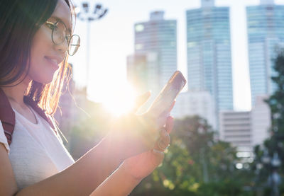 Low angle view of woman using smart phone in city