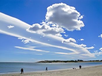 People at beach against blue sky during sunny day