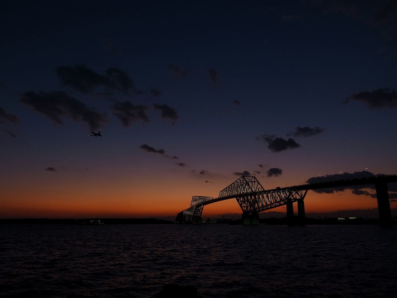 sunset, water, sea, silhouette, sky, scenics, tranquil scene, waterfront, tranquility, connection, beauty in nature, dusk, nature, orange color, built structure, idyllic, architecture, horizon over water, outdoors, bridge - man made structure