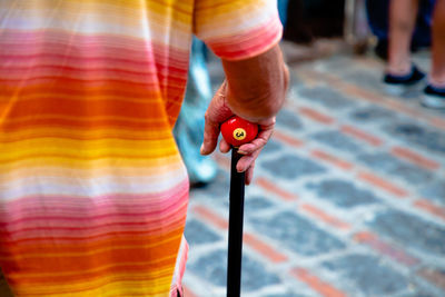 Midsection of man holding walking cane on footpath