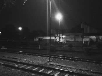 Train on illuminated railroad tracks against sky at night