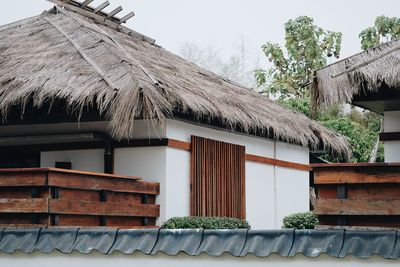 Low angle view of cottage by building against sky