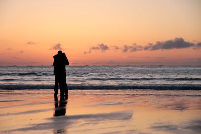 Couple on beach against sunset sky