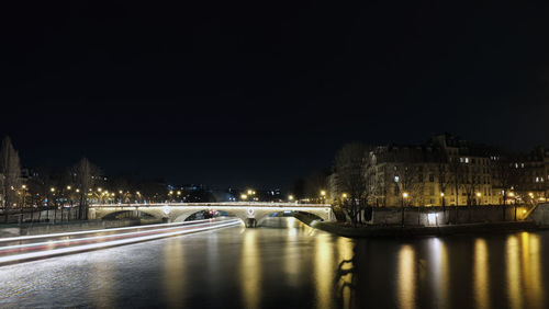 Illuminated bridge over river in city at night