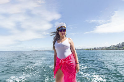 A woman on top of a boat against the sea in the background. 