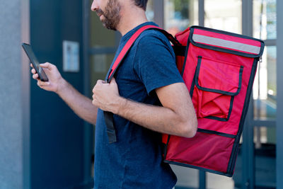Side view of delivery person using mobile phone outdoors