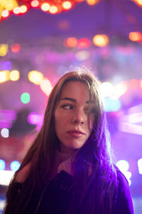 Portrait of smiling woman with illuminated lights at night