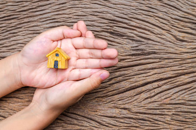 Cropped hands of woman holding model house over table