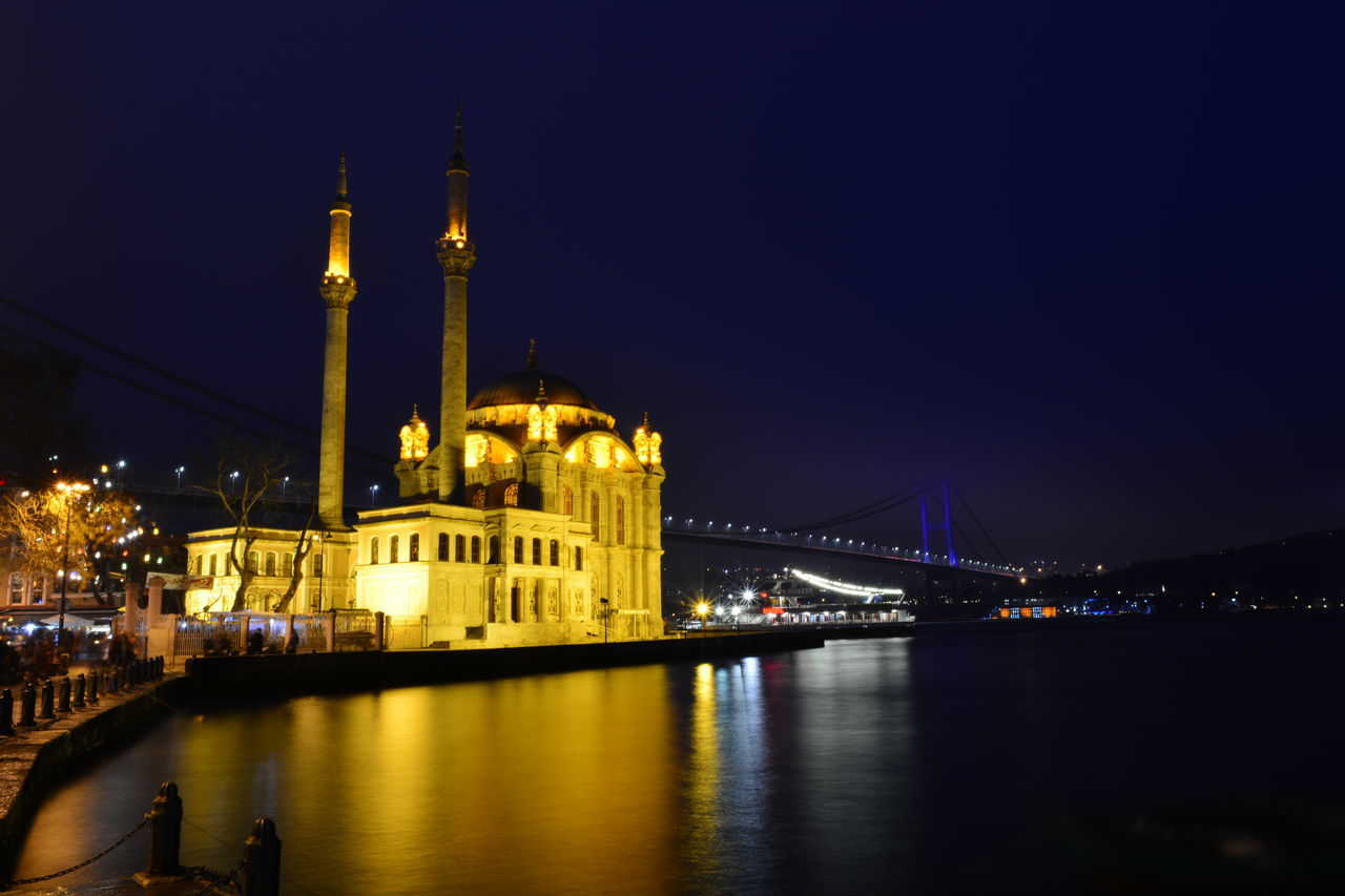 illuminated, architecture, built structure, connection, bridge - man made structure, night, river, city, water, engineering, suspension bridge, building exterior, bridge, transportation, travel destinations, waterfront, international landmark, famous place, capital cities, travel