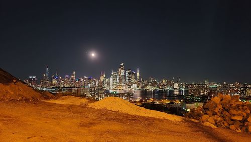 Illuminated buildings in city against clear sky at night