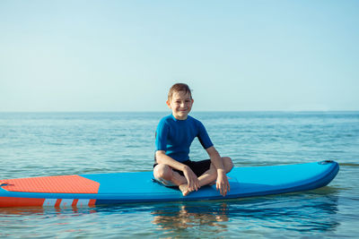 Portrait of smiling man in sea against blue sky