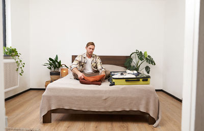 Young woman sitting on bed at home