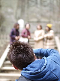 Rear view of man wearing blue hooded shirt bending outdoors