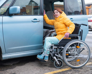 Caucasian woman in a wheelchair gets into the car