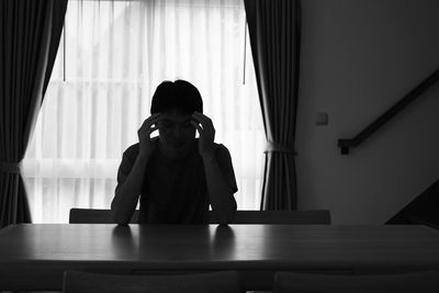 Portrait of man sitting on table at home