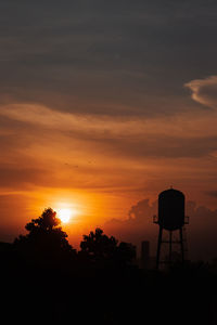 Silhouette water tower against sky during sunset