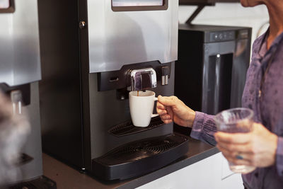 Woman preparing coffee in office kitchen