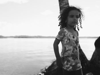 Girl standing by lake against sky