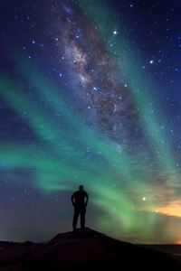 Rear view of silhouette man standing against star field at night