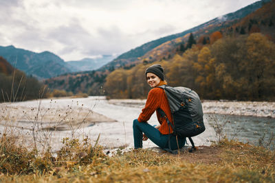 Full length of smiling woman on mountain against sky