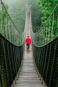 Rear view of man walking on hungin tibetan footbridge