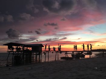 Silhouette people on beach against sky during sunset