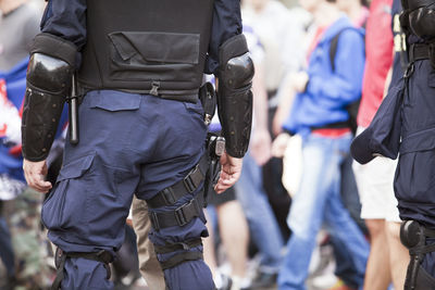 Rear view midsection of female police officer standing with hand on hip