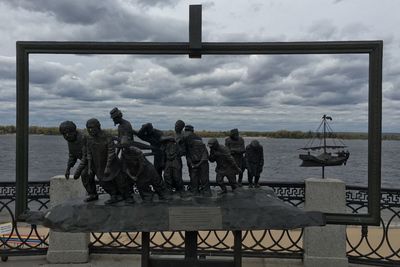 Statue by sea against sky