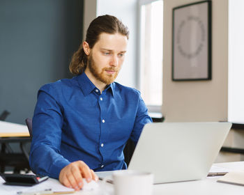 Young focused man freelancer working on laptop computer remotely