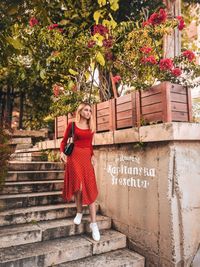 Full length portrait of smiling woman against wall