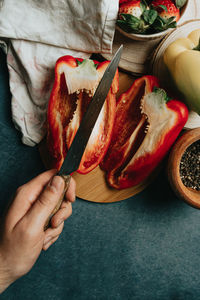 High angle view of hand holding vegetables on table