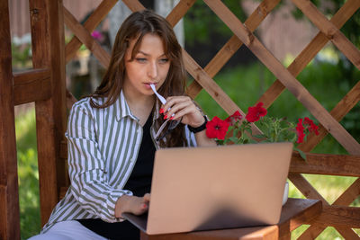 Young woman using mobile phone while sitting on wood