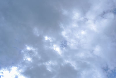 Low angle view of sunlight streaming through clouds