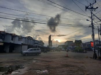 Cars on street by buildings against sky in city