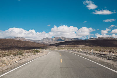 Road by mountains against blue sky