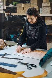 Seamstress at work. dressmaker making clothes and bags in workshop. tailor marking fabric. woman