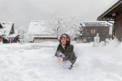 Woman in snow against building during winter