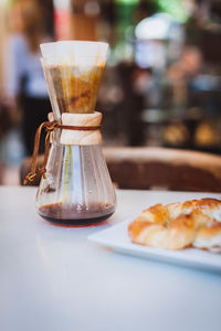 Close-up of coffee filter with croissant on table