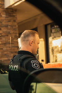 Side view of young man standing in car