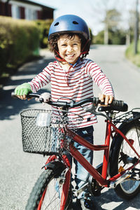 Portrait of happy boy standing with bicycle on footpath at yard